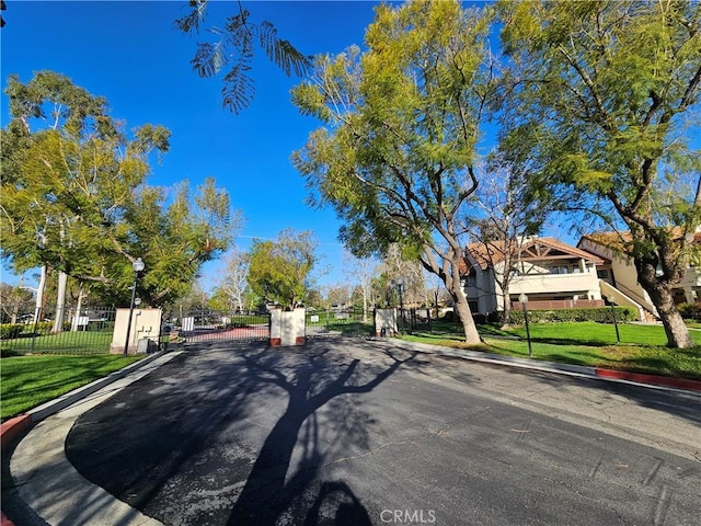 view of road featuring street lights, a gate, curbs, and a gated entry