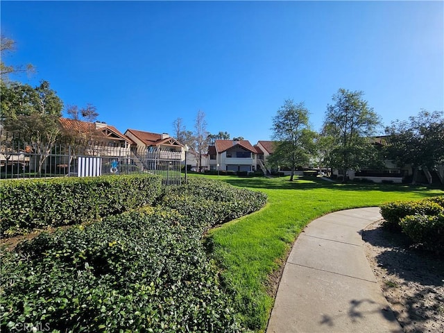 view of community featuring a residential view, a lawn, and fence