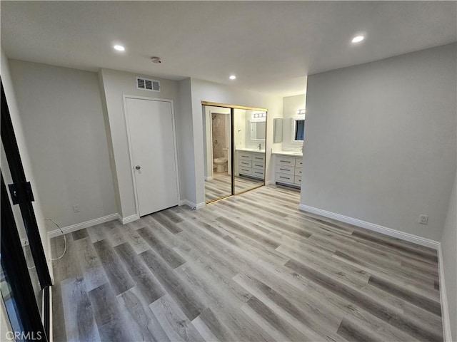 unfurnished bedroom with visible vents, connected bathroom, baseboards, recessed lighting, and light wood-style flooring