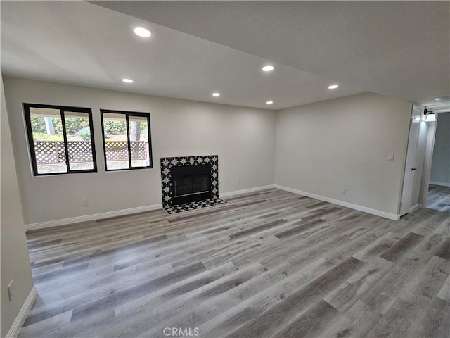 basement featuring recessed lighting, a fireplace, baseboards, and wood finished floors