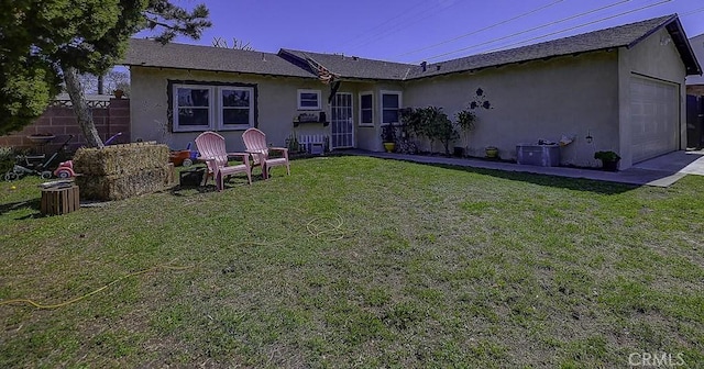 back of property featuring a lawn, a garage, and stucco siding