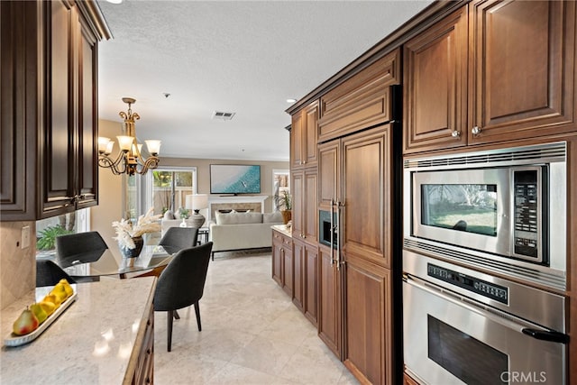 2170 Via Teca Unit 63, San Clemente, CA 92673 - kitchen featuring built in appliances, a chandelier, open floor plan, light stone counters, and light tile patterned floors