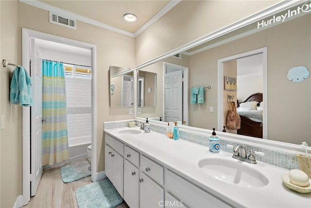 bathroom with a sink, visible vents, double vanity, and crown molding