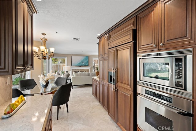 2170 Via Teca Unit 63, San Clemente, CA 92673 - kitchen featuring built in appliances, open floor plan, a chandelier, light stone countertops, and a textured ceiling
