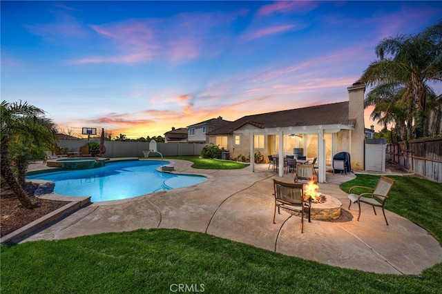 view of pool with a pool with connected hot tub, a patio, a fenced backyard, an outdoor fire pit, and ceiling fan