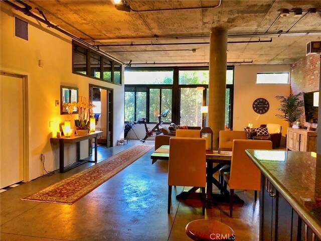 dining space featuring a high ceiling, finished concrete flooring, and visible vents