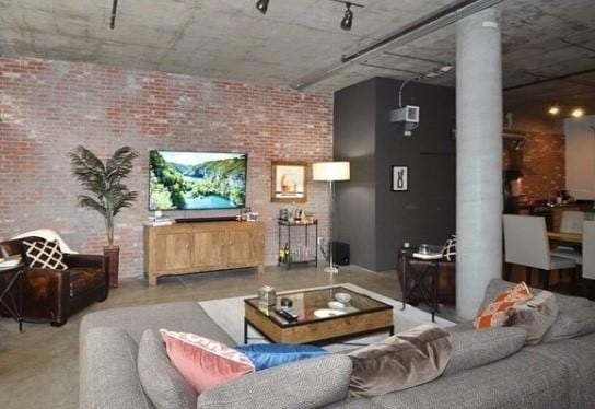 interior space with finished concrete flooring, brick wall, and ornate columns