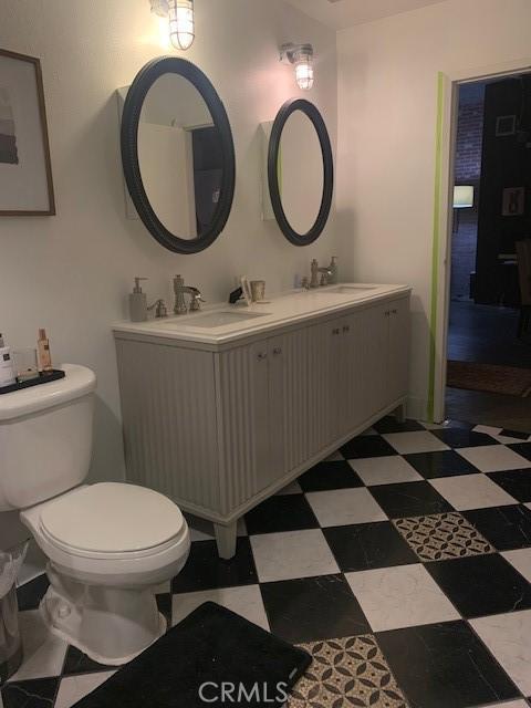 bathroom with tile patterned floors, toilet, double vanity, and a sink