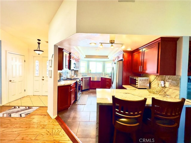 kitchen with backsplash, appliances with stainless steel finishes, and reddish brown cabinets