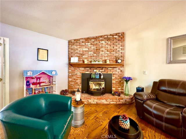 living area featuring vaulted ceiling, a wood stove, and wood finished floors