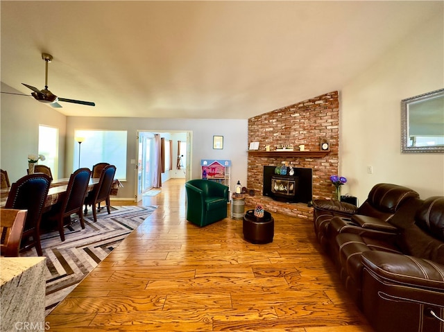 living area featuring hardwood / wood-style floors, lofted ceiling, a fireplace, and ceiling fan