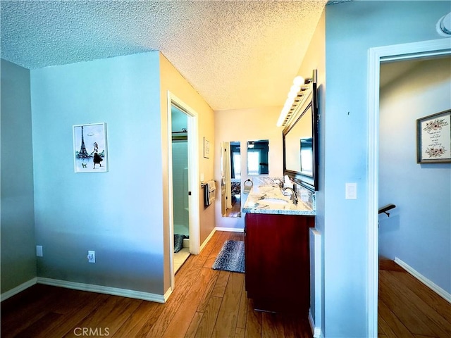 bathroom featuring hardwood / wood-style flooring, baseboards, and a textured ceiling