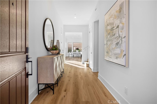 corridor with baseboards and light wood-style floors