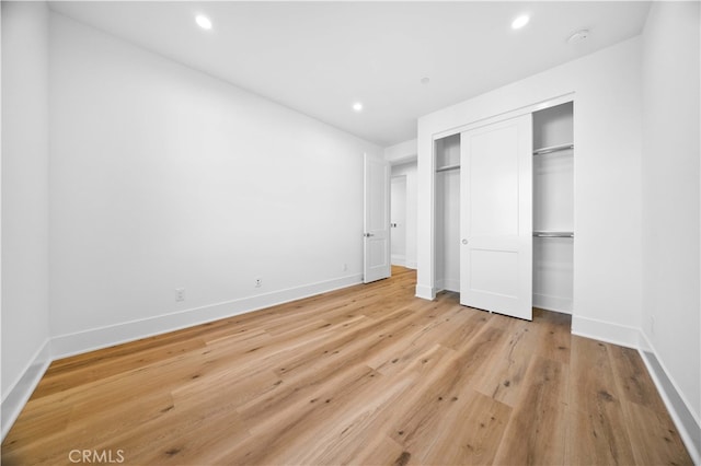 unfurnished bedroom with light wood-style flooring, recessed lighting, baseboards, and a closet