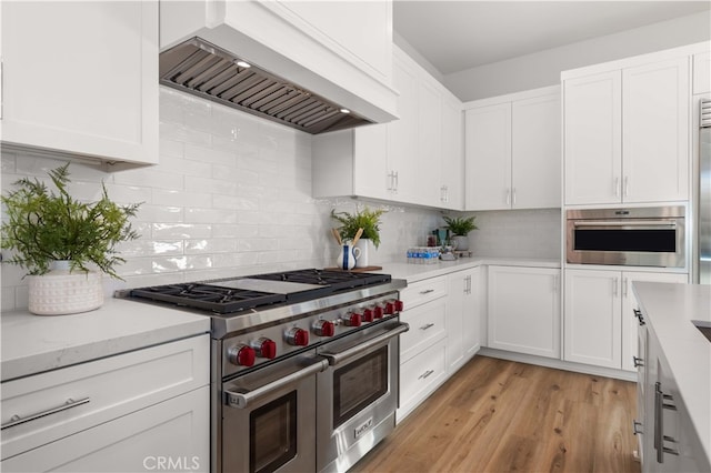 kitchen featuring white cabinets, appliances with stainless steel finishes, and premium range hood