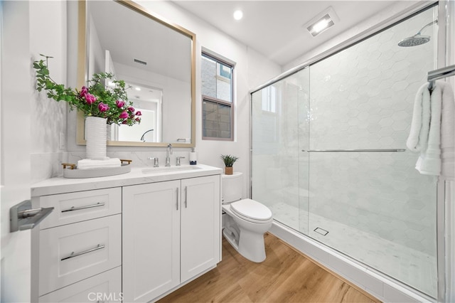 bathroom with visible vents, a shower stall, toilet, wood finished floors, and vanity