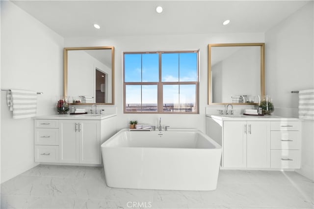 full bath with a soaking tub, two vanities, recessed lighting, and marble finish floor