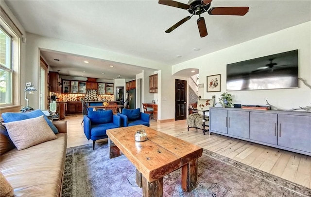 living room with recessed lighting, light wood-type flooring, and arched walkways