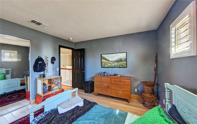 bedroom with visible vents, baseboards, and wood finished floors