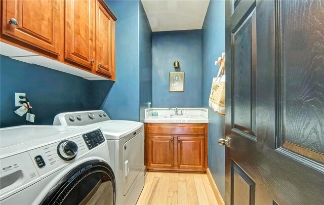 clothes washing area with a sink, light wood-type flooring, cabinet space, and washing machine and dryer