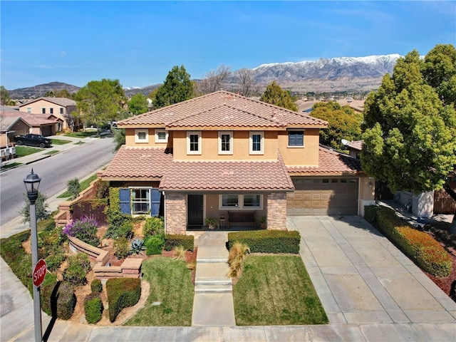 mediterranean / spanish-style house with a tile roof, a mountain view, concrete driveway, and stone siding