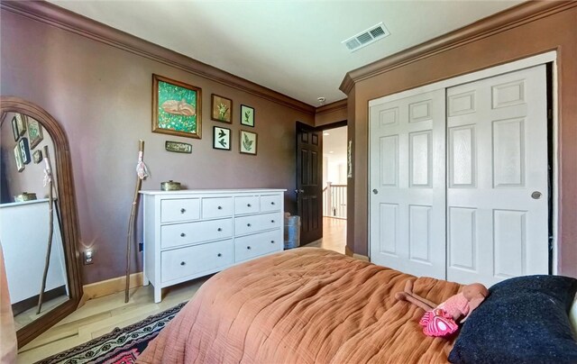 bedroom featuring visible vents, ornamental molding, a closet, light wood-style floors, and baseboards