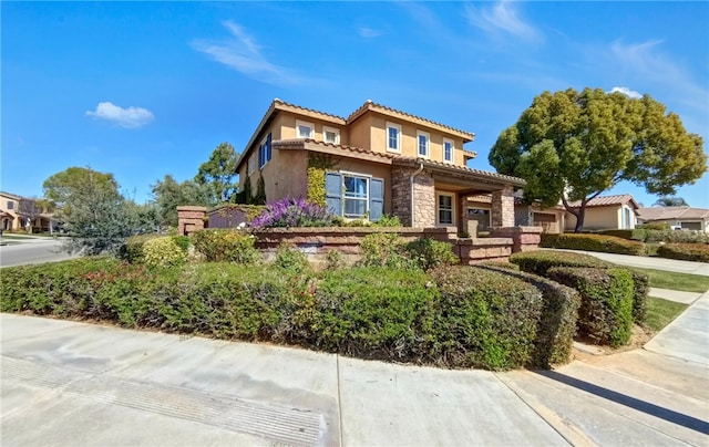 mediterranean / spanish-style house with stucco siding, stone siding, and a tile roof