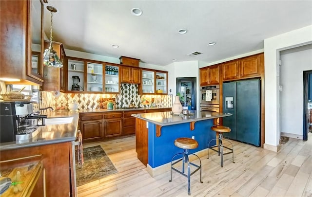 kitchen featuring light wood-type flooring, visible vents, stainless steel double oven, and black fridge