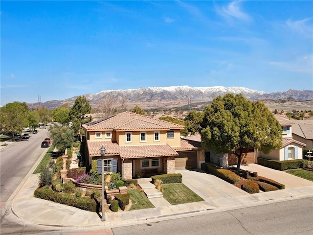 view of front facade with a tile roof, a mountain view, stone siding, and driveway