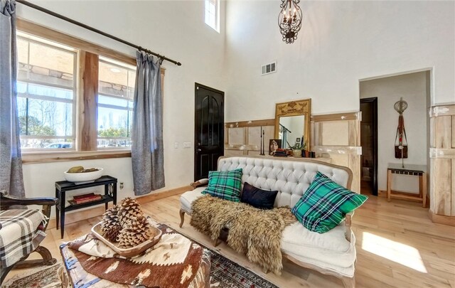 living area with wood finished floors, visible vents, and a towering ceiling