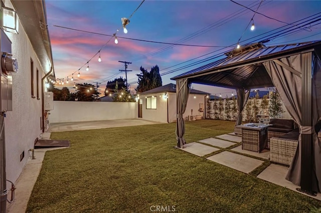 yard at dusk featuring a patio area, a gazebo, and a fenced backyard