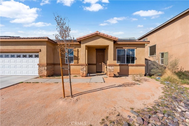 view of front of house with stucco siding, a tile roof, stone siding, roof mounted solar panels, and a garage