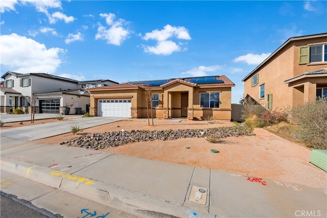 view of front of home featuring stucco siding, a tile roof, roof mounted solar panels, concrete driveway, and a garage