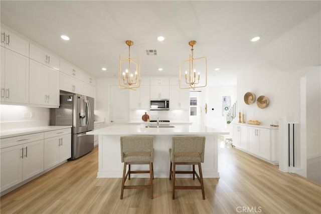 kitchen with light wood-style flooring, recessed lighting, appliances with stainless steel finishes, white cabinets, and light countertops