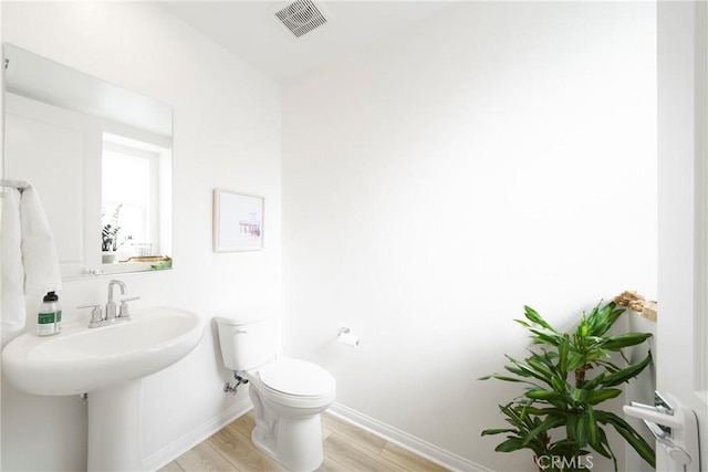 half bath featuring visible vents, toilet, baseboards, and wood finished floors