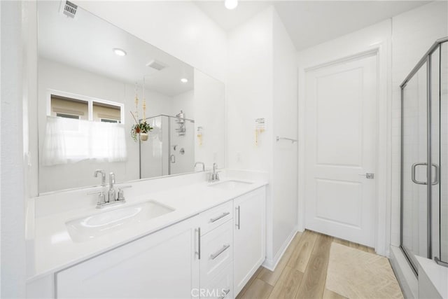 full bathroom with a sink, a stall shower, and wood finished floors