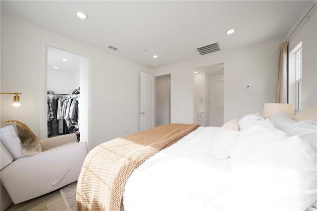 bedroom featuring recessed lighting, visible vents, light wood-style flooring, and a walk in closet