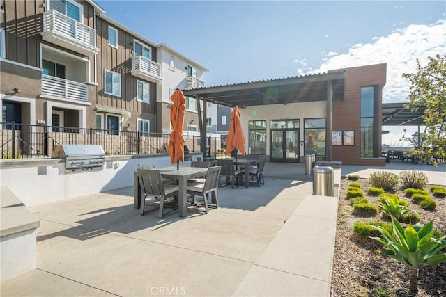 view of community featuring an outdoor kitchen, outdoor dining area, a patio, and fence