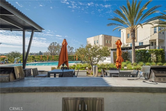 surrounding community featuring a swimming pool, a patio, an outdoor kitchen, and outdoor dry bar