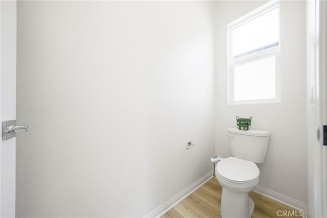 bathroom featuring toilet, baseboards, and wood finished floors