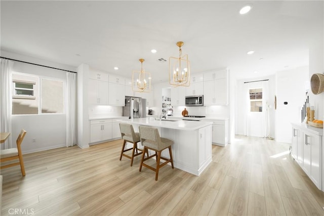 kitchen featuring a sink, light wood finished floors, appliances with stainless steel finishes, and light countertops