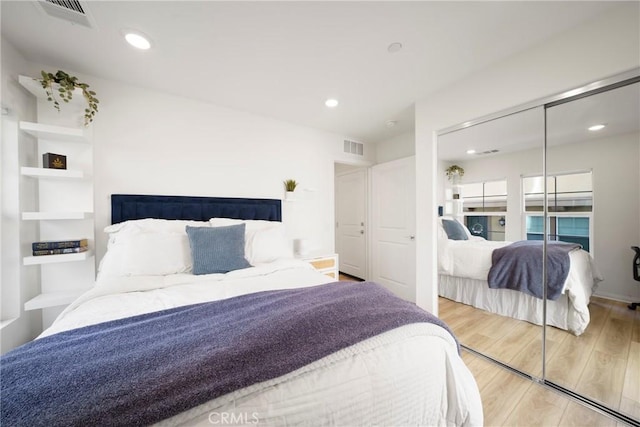 bedroom with a closet, visible vents, recessed lighting, and wood finished floors