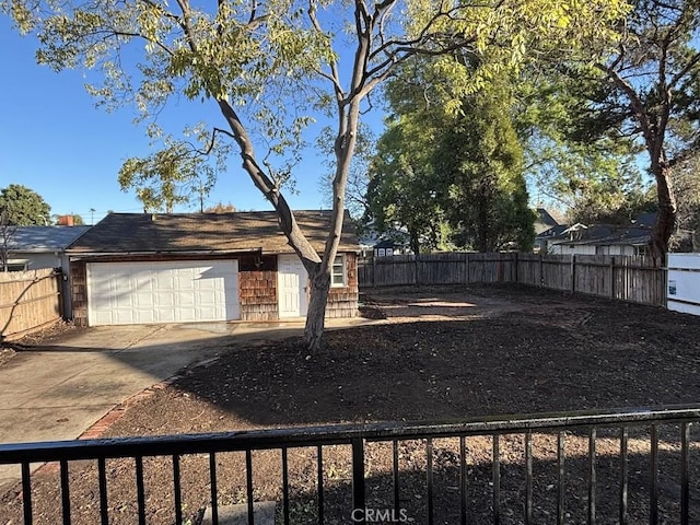 view of yard with concrete driveway, fence, and a garage