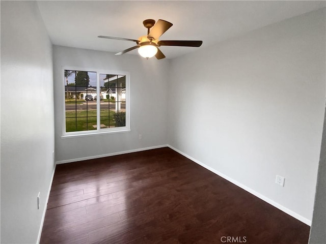 empty room with baseboards, dark wood-style floors, and a ceiling fan