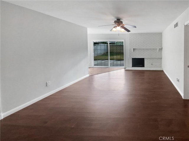 unfurnished living room with wood finished floors, baseboards, visible vents, a ceiling fan, and a fireplace