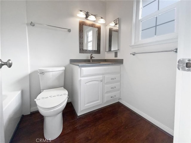 full bathroom with baseboards, toilet, a healthy amount of sunlight, and wood finished floors