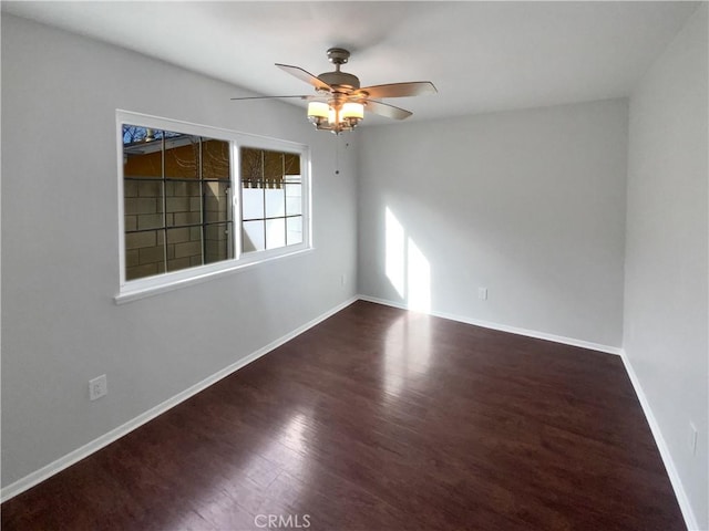 empty room featuring baseboards, wood finished floors, and a ceiling fan