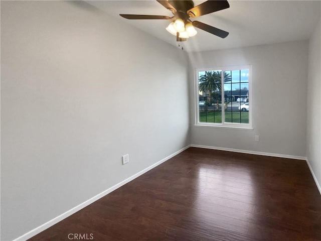 empty room featuring dark wood-style floors, baseboards, and ceiling fan