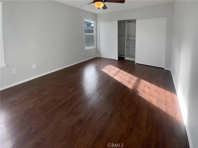 unfurnished bedroom with dark wood finished floors, a ceiling fan, baseboards, and a closet