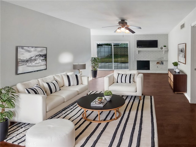 living room featuring wood finished floors, a fireplace, visible vents, and ceiling fan